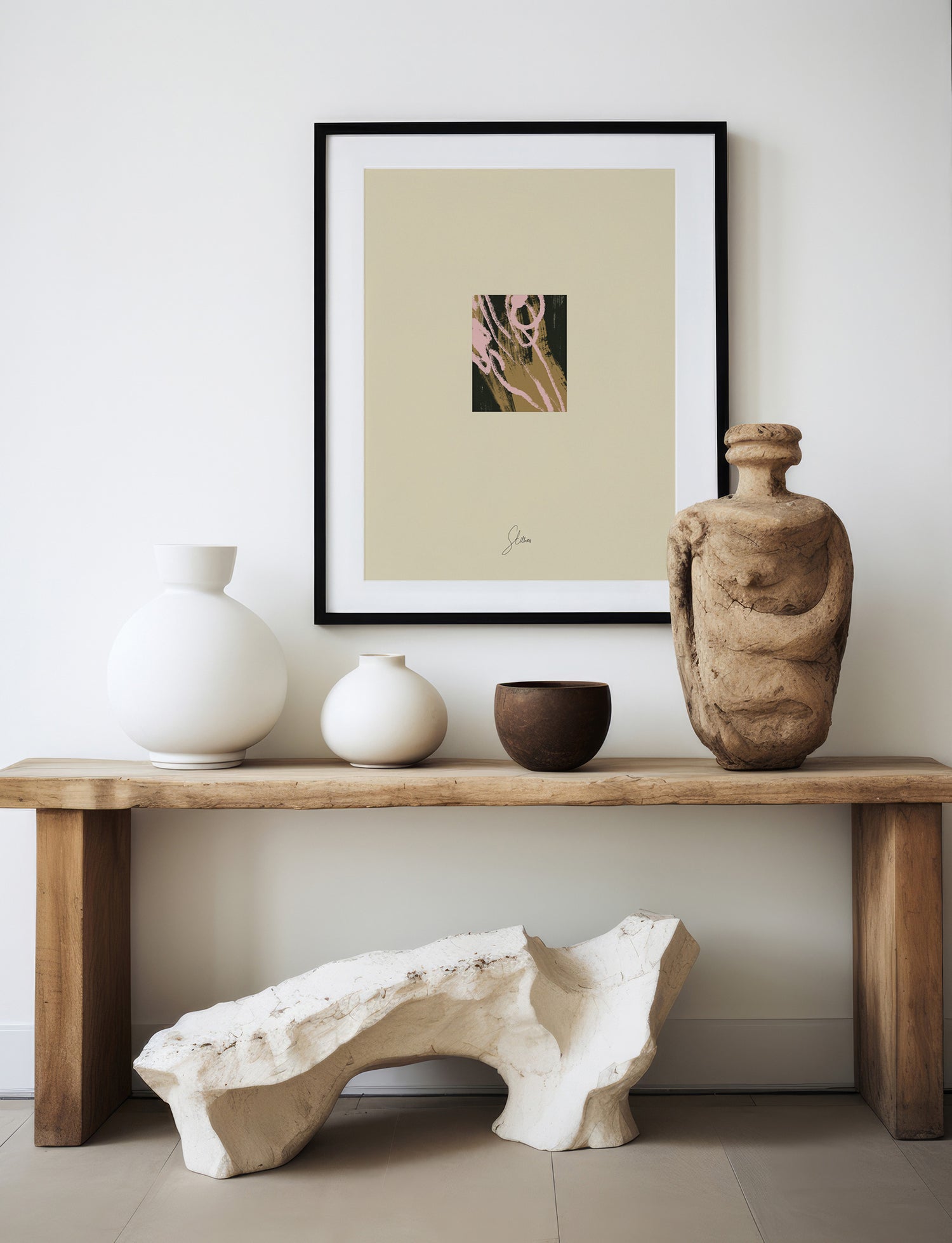 Framed artwork above a wooden console table with decorative vases and sculptures.