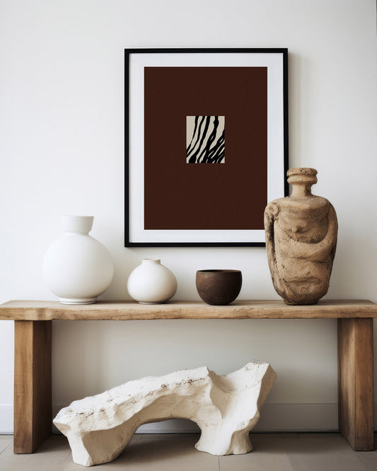 Framed abstract art piece on a wall above a wooden console table with decorative items. anna pepe, artist, contemporary art, printed wall art, framed prints, modern interior decor