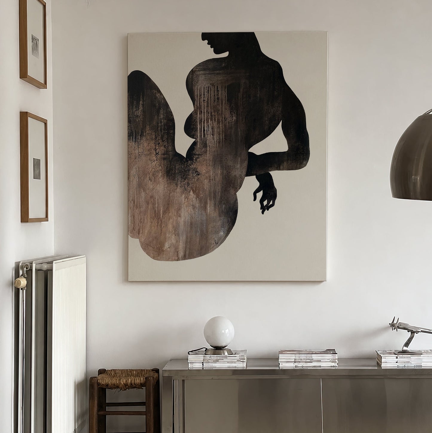 Modern interior with a large abstract painting of a silhouette on a wall, a sideboard with decorative items, and a radiator. large canvas, acrylic on canvas, oversized wall art, abstract art, Anna Pepe, forn Studio