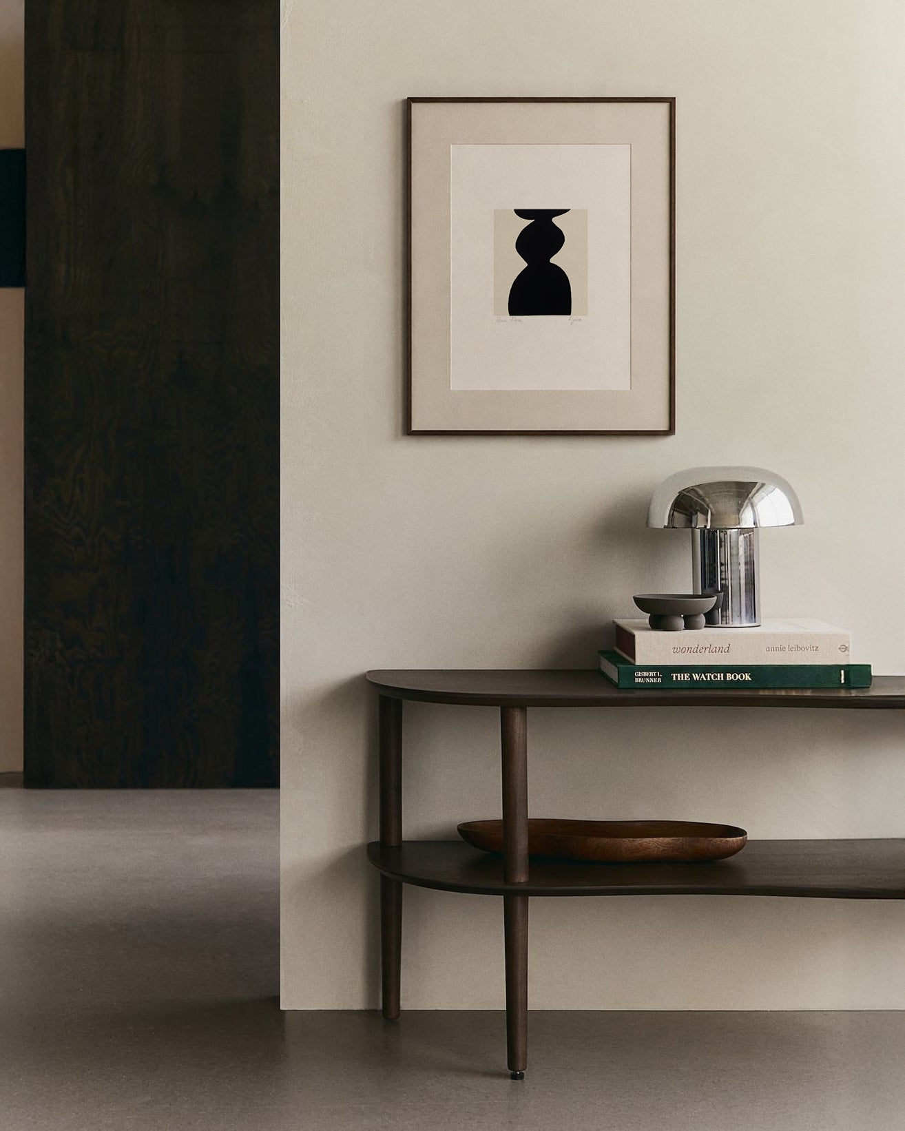 Modern interior with a dark wooden console table against a light wall, featuring a framed abstract art piece. artist anna pepe, forn studio, abstract painting, small art work, female abstract form