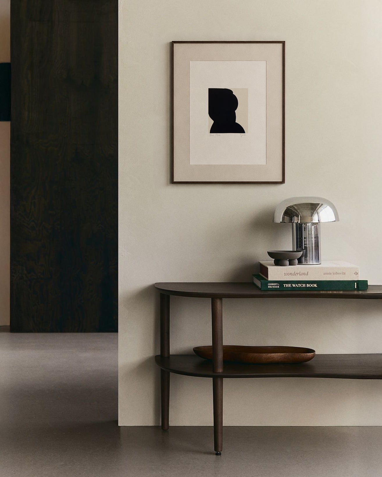 Modern interior with a dark wooden console table against a light wall, featuring a framed abstract art piece. artist anna pepe, forn studio, abstract painting, small art work, female abstract form
