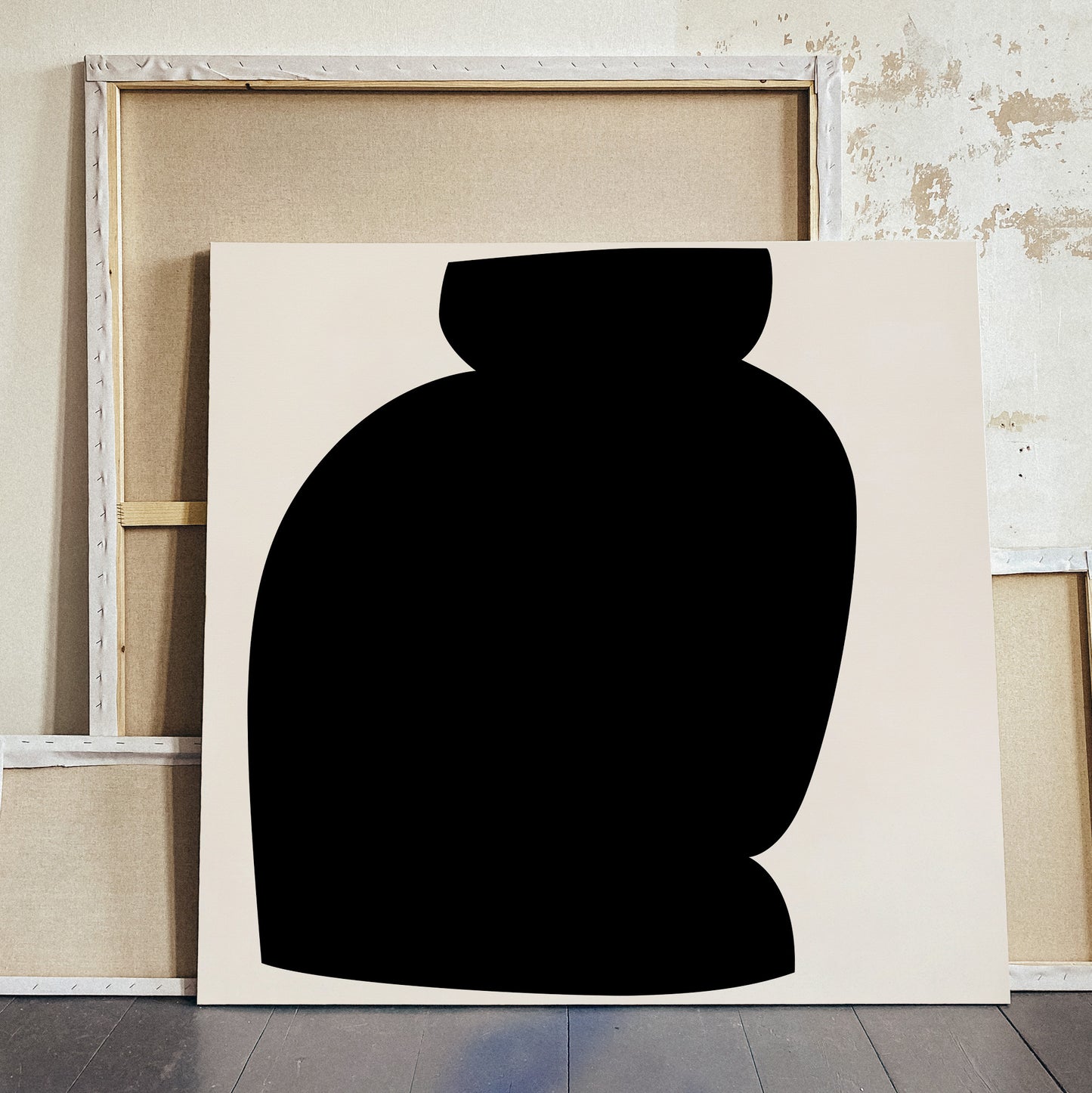 A minimalist abstract canvas print featuring a large black silhouette shape on a warm off-white background, leaning against a rustic wooden frame and distressed wall. large canvas, acrylic on canvas, oversized wall art, abstract art, Anna Pepe, forn Studio
