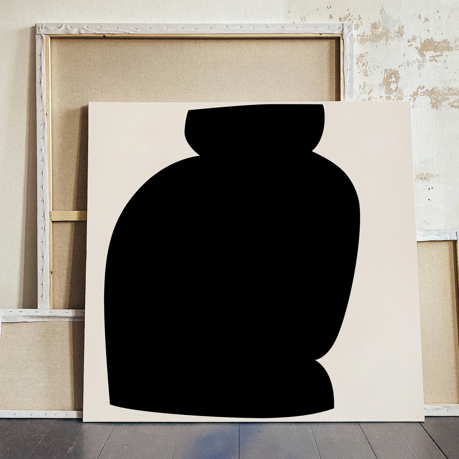 A minimalist abstract canvas print featuring a large black silhouette shape on a warm off-white background, leaning against a rustic wooden frame and distressed wall. large canvas, acrylic on canvas, oversized wall art, abstract art, Anna Pepe, forn Studio
